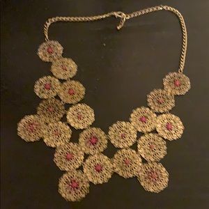 . Gold color with dark pink stone in center .